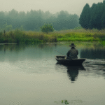 u7934255624_a_photo_of_a_fisherman_in_a_small_boat_on_a_pond__a04e672c-e90e-49c6-a5d2-ad79dfa54cb3_1
